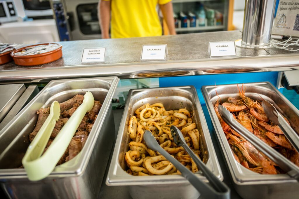 Plateau de gastronomes présentant des gambas grillées, des saucisses catalanes et des calamars cuits à la plancha lors d'une Sortie bateau Canet