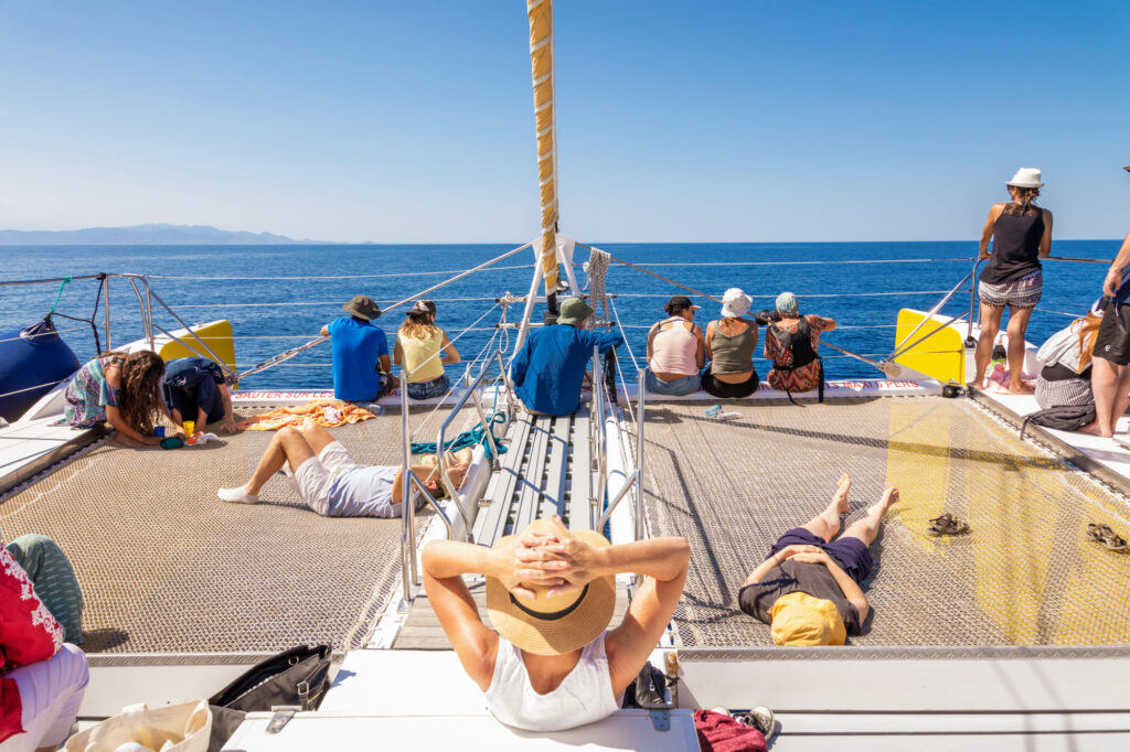 Passagers zen se reposant sur les filets à l'avant du catamaran lors d'un retour de croisière par mer calme vers la Sortie bateau port-vendres