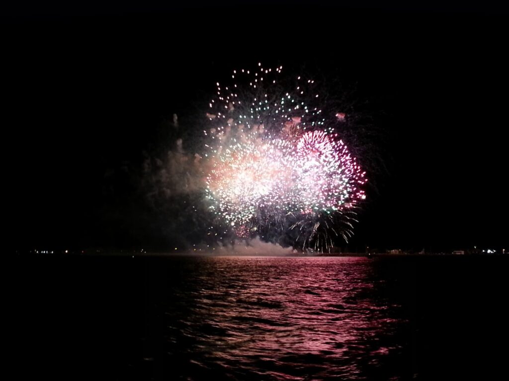 Navire en dérive pendant la nuit avec les dernières lueurs du Feu d’artifice Port Saint-Cyprien 15 août s'estompant à l'horizon au-dessus de la plage