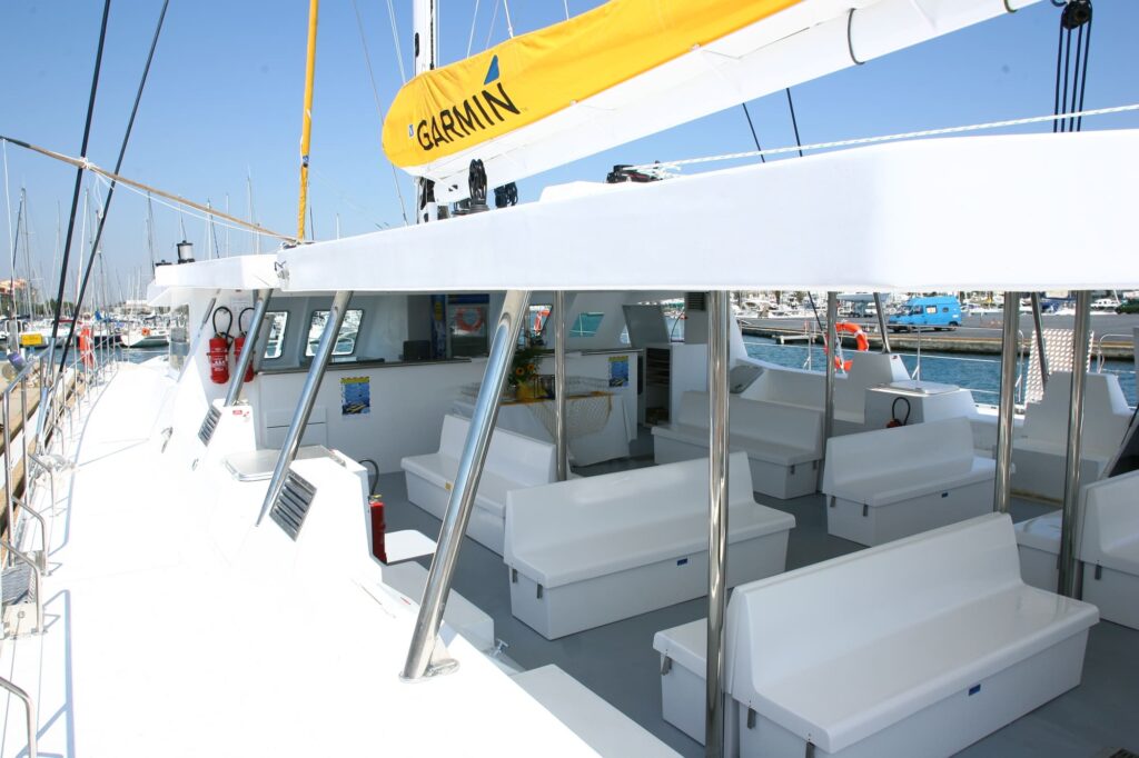 Vue panoramique du pont extérieur spacieux et des banquettes intérieures confortables du catamaran Navivoile en navigation