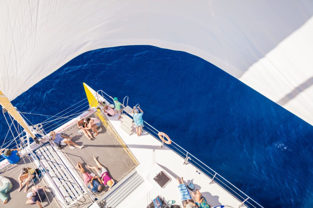 Photo prise en hauteur lors d'une Promenade en mer à Canet en Roussillon. Des passagers paisibles profitent du silence sans moteur sous le gennaker déployé du catamaran Navivoile au large du Barcarès