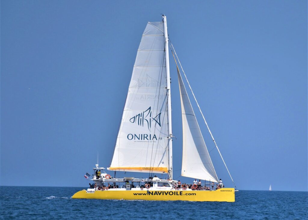 Photo panoramique d'une Promenade en mer à Canet en Roussillon. Le catamaran Navivoile fait route vers le sud, toutes voiles dehors, en direction du grau de l'étang marin de Canet-Saint-Nazaire