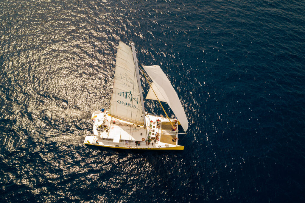 Photo d'une Promenade en mer à Port-Vendres. Le catamaran Navivoile navigue sous voiles par vent de sud-est en face d'Argelès-sur-Mer, devant la plage du Racou et ses célèbres maisonnettes